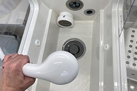 白いシャワーで浴槽を洗う